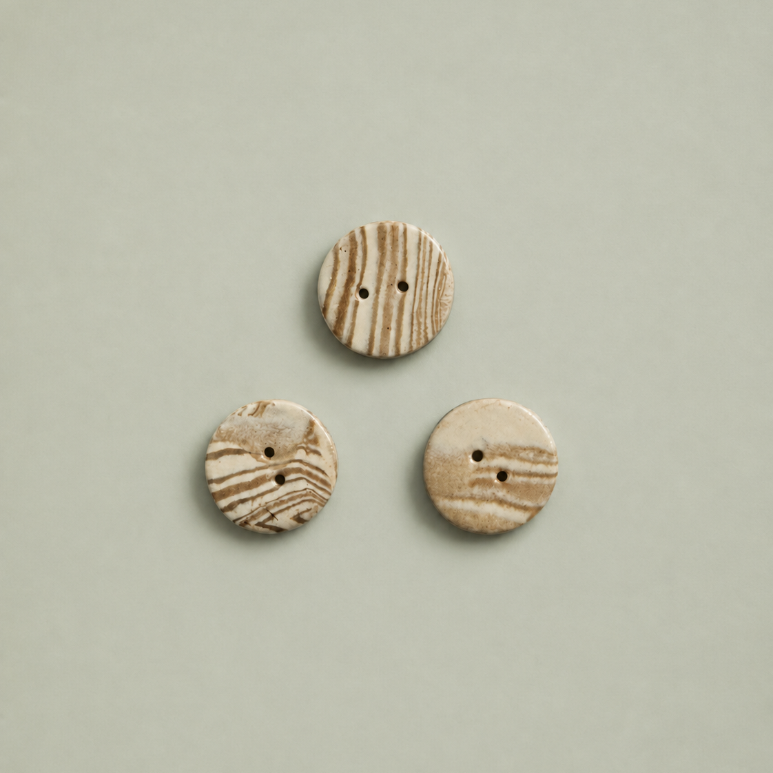 3 Keramik knapper i beige og brun på grøn baggrund
