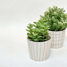 Håndlavede keramik urtepotter med blå striber og tern samt blank glasur, med grønne planter.