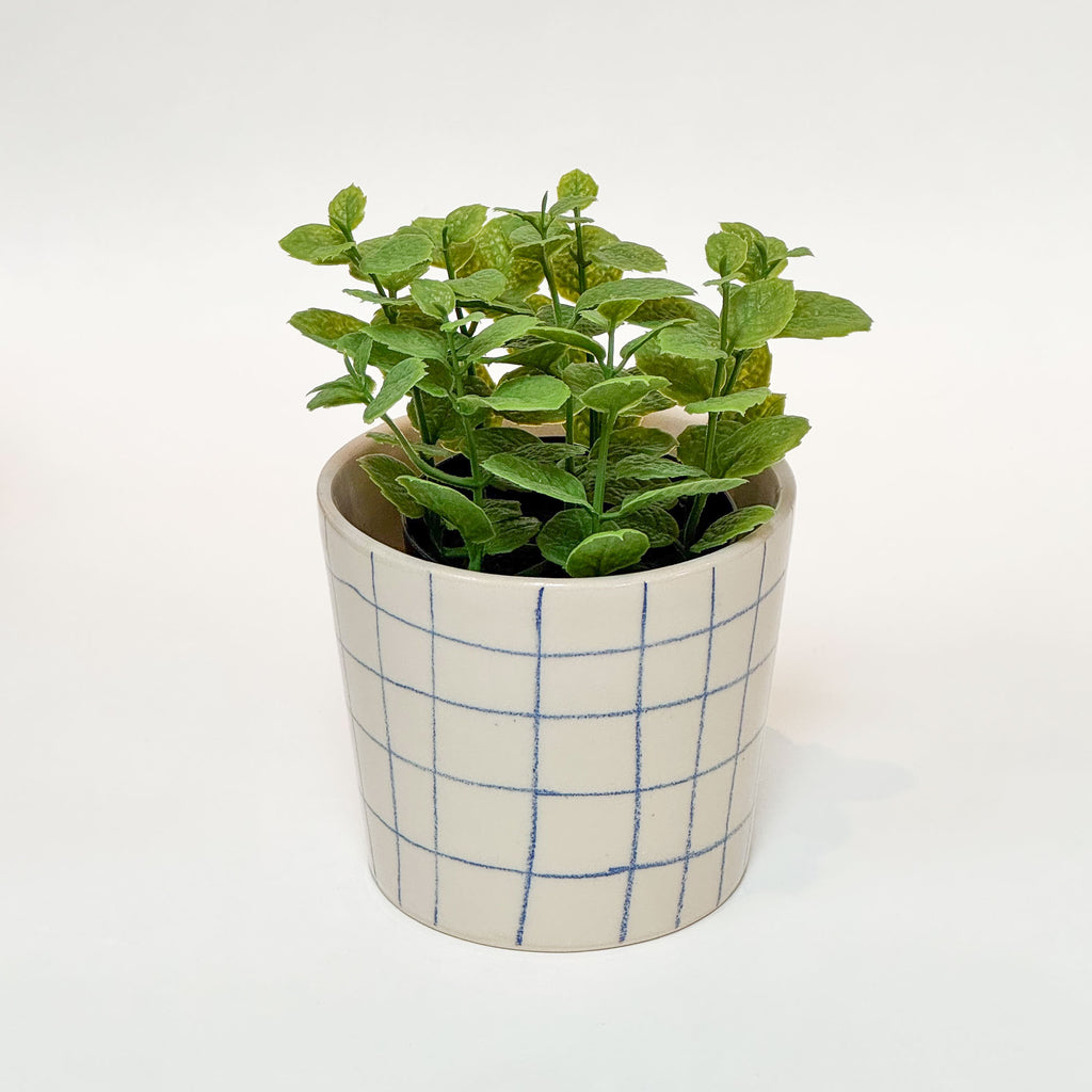 Håndlavet keramik urtepotte med blå tern og blank glasur, med en grøn plante i.