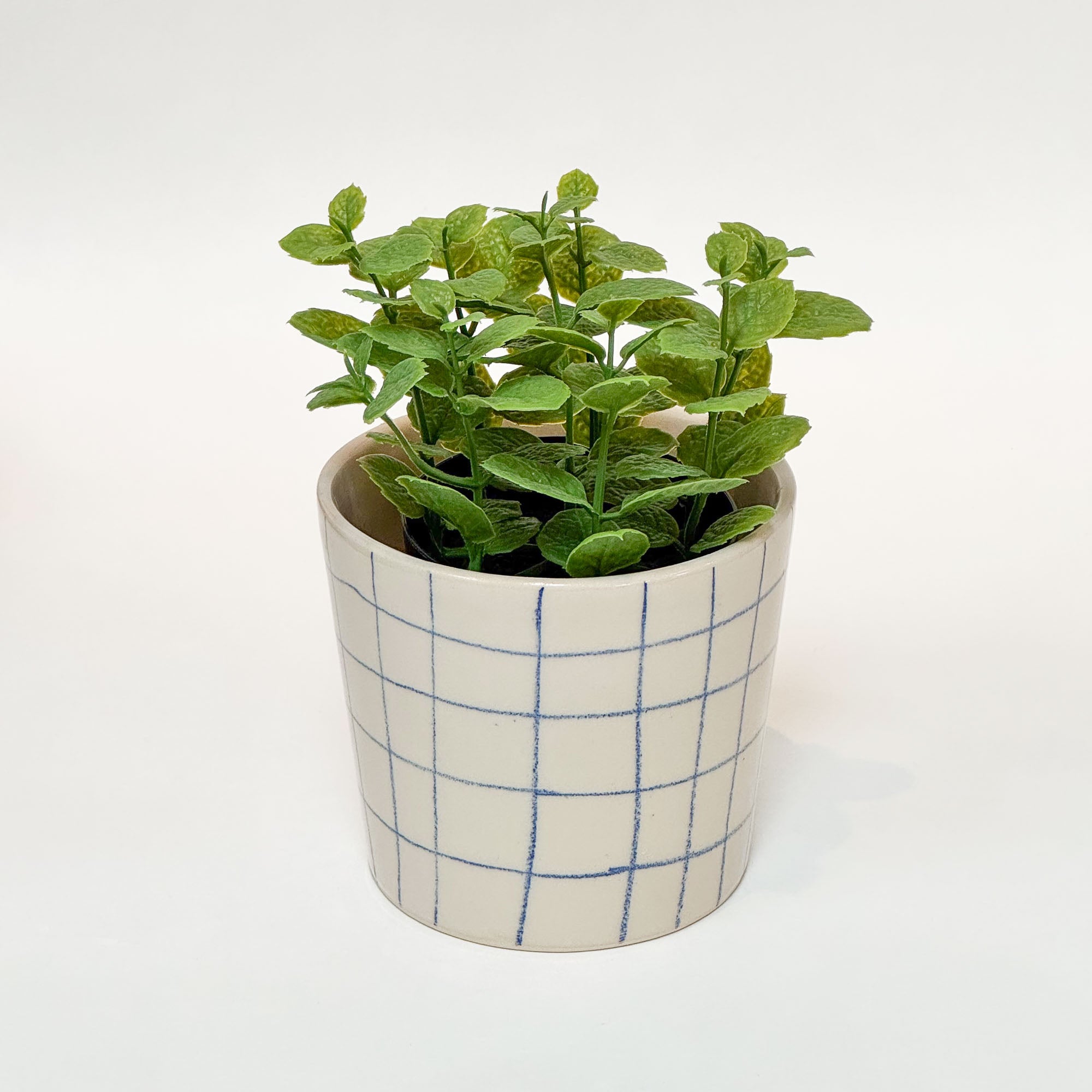 Håndlavet keramik urtepotte med blå tern og blank glasur, med en grøn plante i.