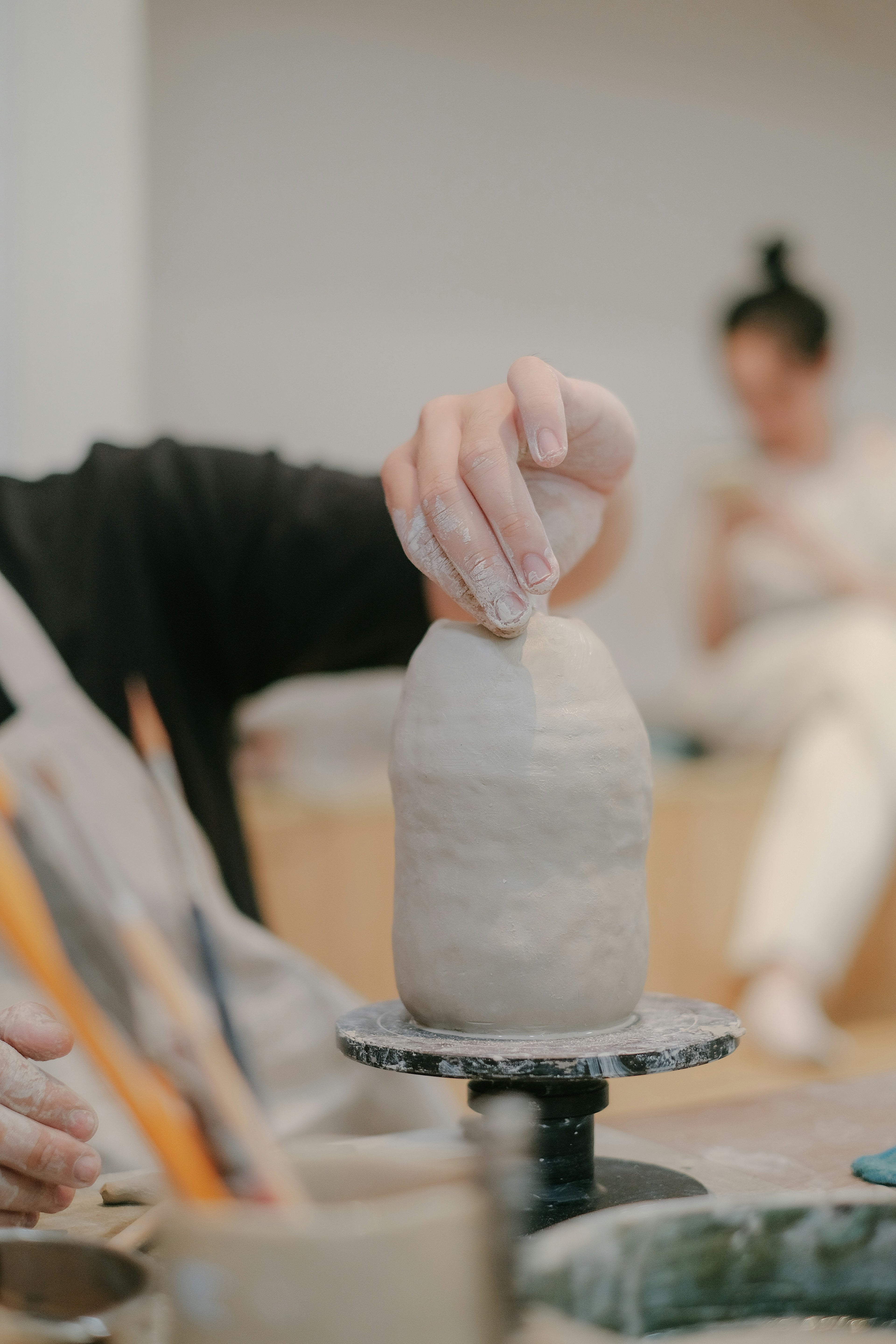 Kvinde modellerer en vase på et keramikkursus hos creatør. 