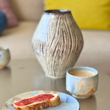 Stor keramik vase med rillet mønster og lys og mærke kontraster. opstillet på morgenmadsbord